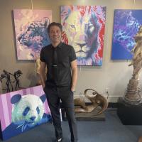 david in front of his artwork. panda, lion, cheetah.